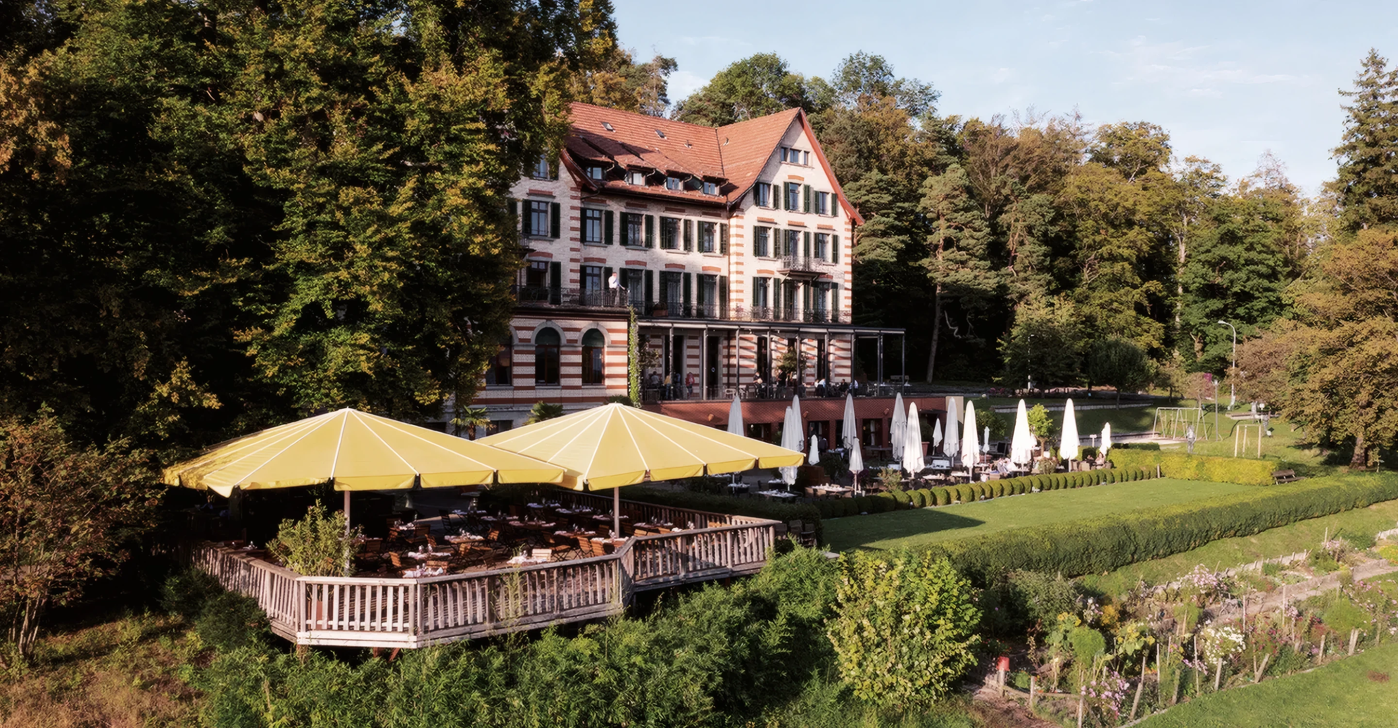Hotel Zürichberg, a historic cream and orange building with a red roof, standing at the edge of woodland above Zurich.